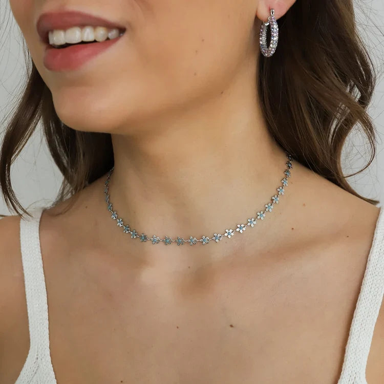Silver flower necklace worn with a hoop earring