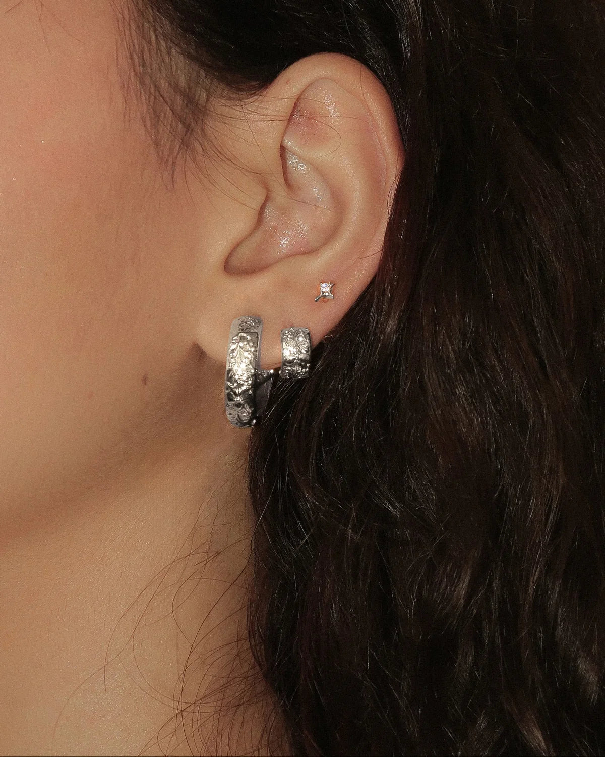 Silver Orchid Hoop worn alongside a smaller hoop and a stud