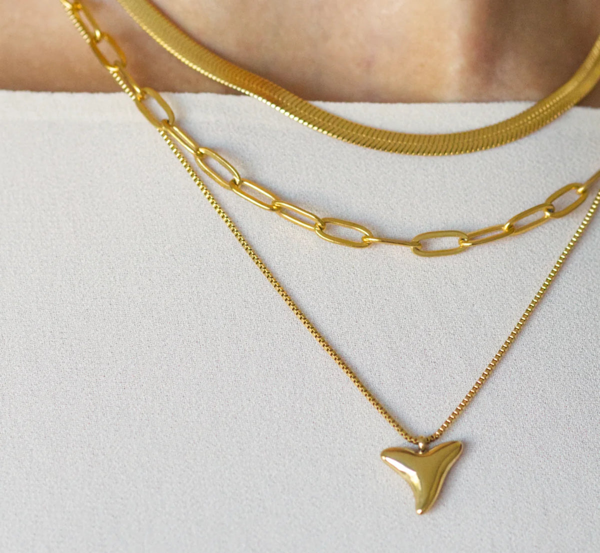 Gold shark tooth necklace worn with layered necklaces